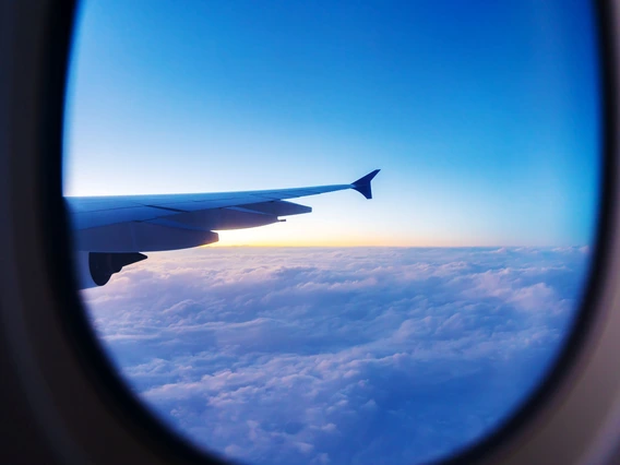 View of airplane wing and colorful sky above clouds seen through a passenger window.”  Let me know if you'd like a version emphasizing the time of day or mood (e.g., sunrise, peaceful, exciting)